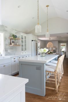 a large kitchen with white cabinets and wooden flooring, along with an island in the middle