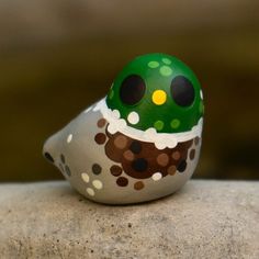 a small green and white object sitting on top of a rock