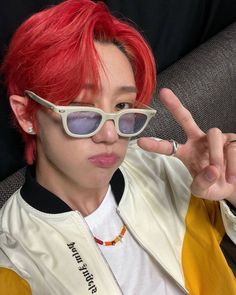 a person with red hair and glasses making the peace sign