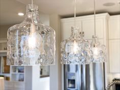 three glass lights hanging from the ceiling in a kitchen