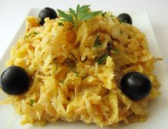 a white plate topped with pasta and olives