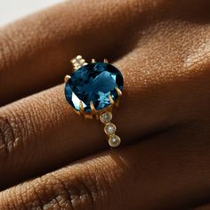 a woman's hand with a blue ring on top of her finger and diamonds around the band