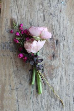 some pink flowers are laying on a piece of wood