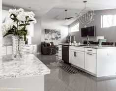 a large kitchen with white cabinets and marble counter tops is pictured in this black and white photo