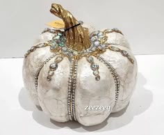 a white pumpkin decorated with gold and jewels