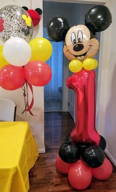 mickey mouse balloon sculpture in the middle of a room with balloons and table cloths