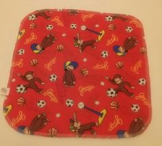 an oven mitt with monkeys and soccer balls on red fabric, sitting on a white surface