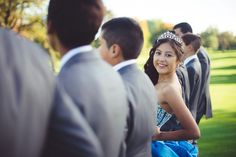 a young woman wearing a tiara standing between two other people in formal wear on the grass