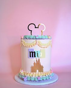 a mickey mouse cake is decorated with pastel colors and frosting for the top