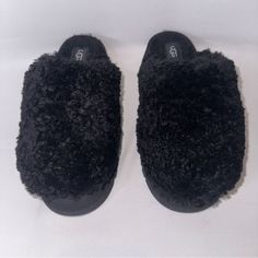 a pair of black slippers sitting on top of a white surface