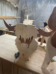 two wooden animals are standing on a workbench, one is carved and the other is made out of plywood