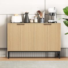 a wooden cabinet sitting next to a potted plant and coffee maker on top of it