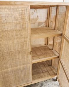 an open cabinet with wicker doors and shelves