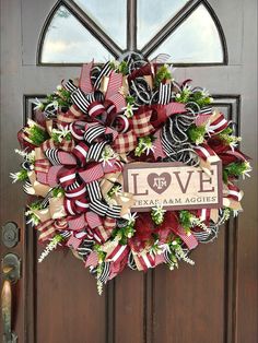 a red and white wreath with love is hanging on the front door to a house