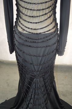 the back of a black dress with beads on it