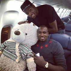 a man sitting on an airplane with a large teddy bear next to him and smiling at the camera