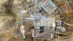 several shopping carts piled on top of each other in an area with dirt and rocks