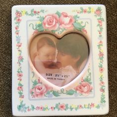 a heart shaped photo frame with pink roses on the front and bottom, in white