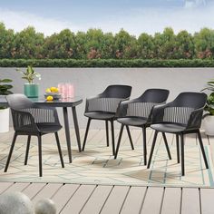 four black chairs and a table on a deck with plants in the backgroud