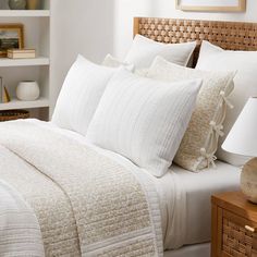 a bed with white linens and pillows in a small room next to a lamp