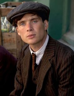 a man in a suit and tie sitting on a bench wearing a hat with his eyes closed