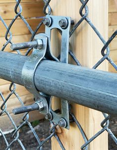 a close up of a chain link fence with a wooden post in the foreground