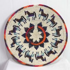 a woven basket is sitting on top of a white chair with an orange and blue design