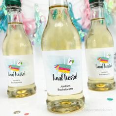 three bottles of liquid sitting next to each other on a white table with confetti streamers