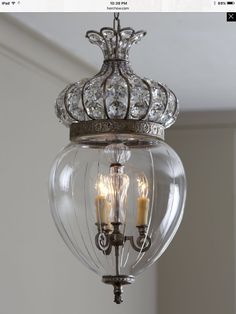 a chandelier hanging from the ceiling with two candles in it and some lights on