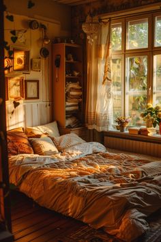 an unmade bed sitting in front of a window next to a dresser and potted plant