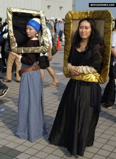 two women in costume holding up pictures with gold frames on their heads and one woman wearing a blue headband