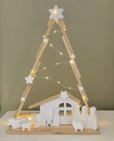 a small wooden christmas tree with lights and nativity figurines in front of it