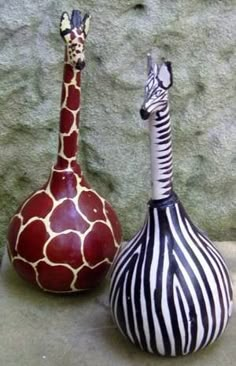 two zebra and giraffe shaped vases sitting next to each other on the ground