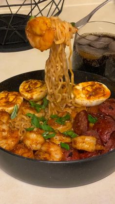 a pan filled with noodles and shrimp being lifted from the skillet by chopsticks