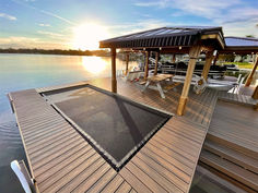 a dock with chairs and an awning on it at the end of a body of water