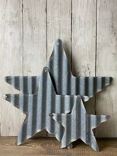 two metal stars are sitting on a wooden table next to a white painted wood wall