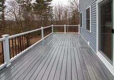 a wooden deck with white railings next to trees