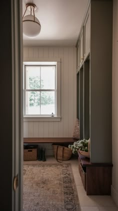 an empty room with a bench, window and rug on the floor in front of it