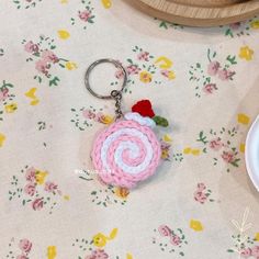 a pink and white crocheted keychain with a red flower on it