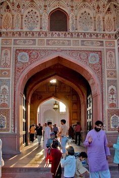 many people are walking up and down the stairs in front of an ornate building with arches