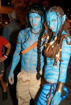 two people with blue paint on their faces and body are standing next to each other