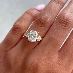 a woman's hand holding a three stone diamond ring