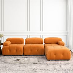 an orange couch sitting on top of a rug in front of a white wall next to a table