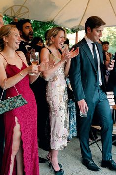 a group of people standing next to each other holding wine glasses