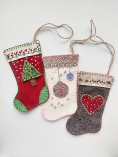 three christmas stockings hanging from strings on a white surface