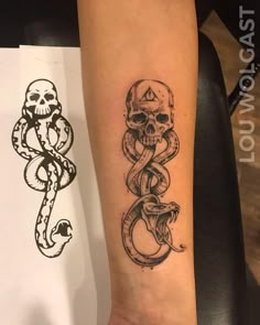 a skull and snake tattoo on the arm