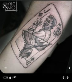 a black and white photo of a man's arm with a joker playing card tattoo on it