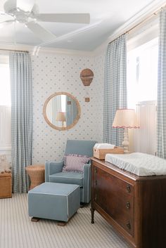 a baby's room with a blue chair, bed and mirror on the wall