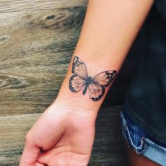 a woman's wrist with a small butterfly tattoo on the left side of her arm