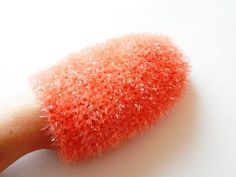 a close up of a brush on a white surface with orange and pink hair flecks